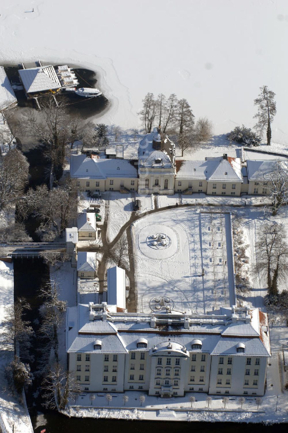 Berlin from above - Blick auf den winterlich verschneite Schloß Köpenick. Die spätere Schlossinsel Köpenick wurde schon zu urgeschichtlicher Zeit besiedelt und ist neben Spandau und Cölln eine der frühesten Siedlungsgebiete des heutigen Berlins. Hier fanden sich später slawische Burgwälle, eine slawische Burg entstand im 8. oder 9. Jahrhundert. Mehrere Nachfolgebauten folgten, darunter auch eine spätmittelalterliche Kastellburg. Der Slawenfürst Jaxa von Köpenick regierte hier im 12. Jahrhundert.Für Kurprinz Friedrich (später Kurfürst Friedrich III. von Brandenburg, dann auch König Friedrich I. in Preußen) wurde das Schloss ab 1677 erweitert. Als Architekt war hierbei Rutger van Langervelt, ein geborener Holländer aus Nimwegen, verantwortlich. Der nördliche Pavillon entstand in den Jahren 1679–1682. Der Architekt Johann Arnold Nering folgte van Langervelt 1684 beim Schlossbau und ließ den Wirtschaftsflügel mit der reformierten Schlosskirche (eingeweiht am 6. Januar 1685) und zuvor bereits das Hoftor (1682) entstehen. Friedrich bewohnte das Schloss später mit seiner Gemahlin Elisabeth Henriette von Hessen-Kassel, die den Anstoß zum Bau der Kirche gegeben haben soll.