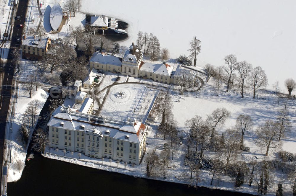 Aerial image Berlin - Blick auf den winterlich verschneite Schloß Köpenick. Die spätere Schlossinsel Köpenick wurde schon zu urgeschichtlicher Zeit besiedelt und ist neben Spandau und Cölln eine der frühesten Siedlungsgebiete des heutigen Berlins. Hier fanden sich später slawische Burgwälle, eine slawische Burg entstand im 8. oder 9. Jahrhundert. Mehrere Nachfolgebauten folgten, darunter auch eine spätmittelalterliche Kastellburg. Der Slawenfürst Jaxa von Köpenick regierte hier im 12. Jahrhundert.Für Kurprinz Friedrich (später Kurfürst Friedrich III. von Brandenburg, dann auch König Friedrich I. in Preußen) wurde das Schloss ab 1677 erweitert. Als Architekt war hierbei Rutger van Langervelt, ein geborener Holländer aus Nimwegen, verantwortlich. Der nördliche Pavillon entstand in den Jahren 1679–1682. Der Architekt Johann Arnold Nering folgte van Langervelt 1684 beim Schlossbau und ließ den Wirtschaftsflügel mit der reformierten Schlosskirche (eingeweiht am 6. Januar 1685) und zuvor bereits das Hoftor (1682) entstehen. Friedrich bewohnte das Schloss später mit seiner Gemahlin Elisabeth Henriette von Hessen-Kassel, die den Anstoß zum Bau der Kirche gegeben haben soll.