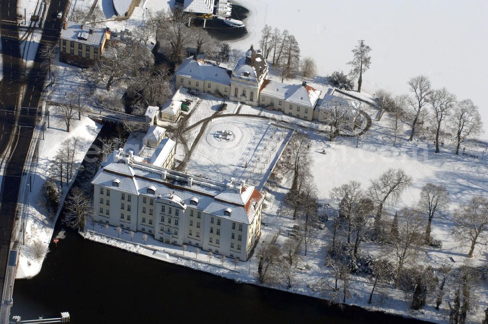 Aerial photograph Berlin - Blick auf den winterlich verschneite Schloß Köpenick. Die spätere Schlossinsel Köpenick wurde schon zu urgeschichtlicher Zeit besiedelt und ist neben Spandau und Cölln eine der frühesten Siedlungsgebiete des heutigen Berlins. Hier fanden sich später slawische Burgwälle, eine slawische Burg entstand im 8. oder 9. Jahrhundert. Mehrere Nachfolgebauten folgten, darunter auch eine spätmittelalterliche Kastellburg. Der Slawenfürst Jaxa von Köpenick regierte hier im 12. Jahrhundert.Für Kurprinz Friedrich (später Kurfürst Friedrich III. von Brandenburg, dann auch König Friedrich I. in Preußen) wurde das Schloss ab 1677 erweitert. Als Architekt war hierbei Rutger van Langervelt, ein geborener Holländer aus Nimwegen, verantwortlich. Der nördliche Pavillon entstand in den Jahren 1679–1682. Der Architekt Johann Arnold Nering folgte van Langervelt 1684 beim Schlossbau und ließ den Wirtschaftsflügel mit der reformierten Schlosskirche (eingeweiht am 6. Januar 1685) und zuvor bereits das Hoftor (1682) entstehen. Friedrich bewohnte das Schloss später mit seiner Gemahlin Elisabeth Henriette von Hessen-Kassel, die den Anstoß zum Bau der Kirche gegeben haben soll.