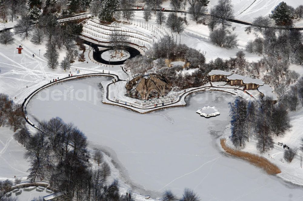 Aerial photograph Berlin - Blick auf die winterlich verschneiten Britzer Garten.Der Britzer Garten, benannt nach dem Berliner Ortsteil Britz, wurde für die Bundesgartenschau 1985 angelegt, um der damals vom Umland abgeschnittenen Bevölkerung im Süden West-Berlins einen neuen Landschaftspark zu bieten.Der Britzer Garten wurde auf Ackerflächen und Kleingartenkolonien angelegt; weitestgehend wurden jedoch vorhandene Kleingartenkolonien erhalten. Er befindet sich am südwestlichen Rand des damaligen Berliner Bezirkes Neukölln und grenzt an den Bezirk Tempelhof mit dem Ortsteil Mariendorf an. Er wird durch die Hauptstraßenachsen Mariendorfer Damm, Mohriner Allee, Buckower Damm und Alt-Buckow / Marienfelder Allee eingerahmt. Am Rand dieser Hauptstraßen befindet sich meist offene Wohnbebauung. Noch im Eröffnungsjahr 1985 bestand die planerische Absicht, eine Verlängerung der Berliner Stadtautobahn von der Anschlussstelle Gradestraße durch das Gartengelände hindurch bis zur Berliner Stadtgrenze zu bauen, um dort einen neuen Grenzübergang mit Weiterführung zum Berliner Ring einrichten zu können.