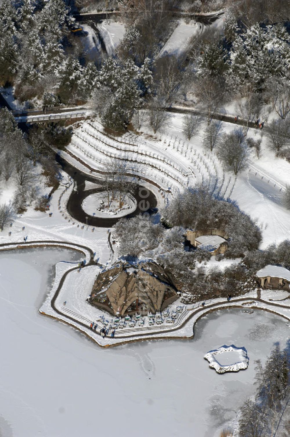 Aerial image Berlin - Blick auf die winterlich verschneiten Britzer Garten.Der Britzer Garten, benannt nach dem Berliner Ortsteil Britz, wurde für die Bundesgartenschau 1985 angelegt, um der damals vom Umland abgeschnittenen Bevölkerung im Süden West-Berlins einen neuen Landschaftspark zu bieten.Der Britzer Garten wurde auf Ackerflächen und Kleingartenkolonien angelegt; weitestgehend wurden jedoch vorhandene Kleingartenkolonien erhalten. Er befindet sich am südwestlichen Rand des damaligen Berliner Bezirkes Neukölln und grenzt an den Bezirk Tempelhof mit dem Ortsteil Mariendorf an. Er wird durch die Hauptstraßenachsen Mariendorfer Damm, Mohriner Allee, Buckower Damm und Alt-Buckow / Marienfelder Allee eingerahmt. Am Rand dieser Hauptstraßen befindet sich meist offene Wohnbebauung. Noch im Eröffnungsjahr 1985 bestand die planerische Absicht, eine Verlängerung der Berliner Stadtautobahn von der Anschlussstelle Gradestraße durch das Gartengelände hindurch bis zur Berliner Stadtgrenze zu bauen, um dort einen neuen Grenzübergang mit Weiterführung zum Berliner Ring einrichten zu können.