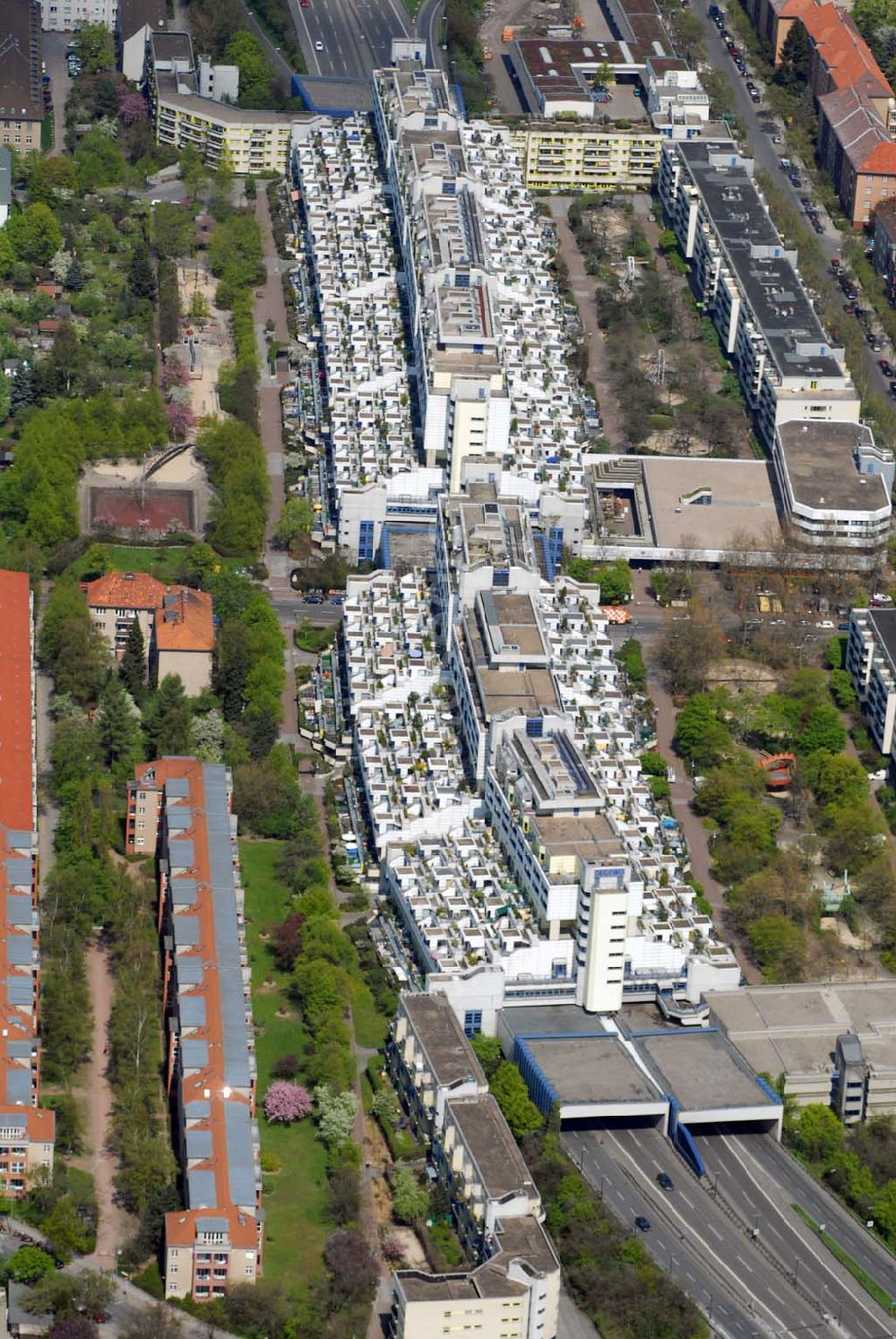 Berlin - Wilmersdorf from above - Blick auf den Wohnpark an der Schlangenbader Strasse in Wilmersdorf. 1970/1971 begannen die ersten Bauarbeiten des südlichen Abzweigs (A 104) der Stadtautobahn A 100. Auf einem Areal von etwa 44.000 m², welches im westlichen Teil die Autobahn A 104 überschneidet, konnte nun die Autobahnüberbauung Schlangenbader Straße geplant werden. Zunächst fungierte das Projekt unter dem Namen Wohnpark Wilmersdorf.Die heutige Autobahnüberbauung umschließt die Autobahn A 104 auf einer Länge von 600 m in ihrem Nord-Süd-Verlauf und verläuft analog der Fahrbahn in leichtem Winkel gebogen. Die Erbauung des Gesamtprojekts fand zwischen 1976 und 1980 statt. Die Bauausführung erfolgte durch mehrere Firmen in einer Arbeitsgemeinschaft. Beteiligt waren die Firmen Burgert-Neue Bauhütte AG, Ed.Züblin AG, Schälerbau Berlin, Bruno Ansorge, Lindow & Co, Richter & Schädel, Sager & Woerner(SAWOE), Anton Schmittlein AG, Gottlieb Tesch GmbH, Karl Tobias GmbH, F.C. Trapp und Wiemer & Trachte