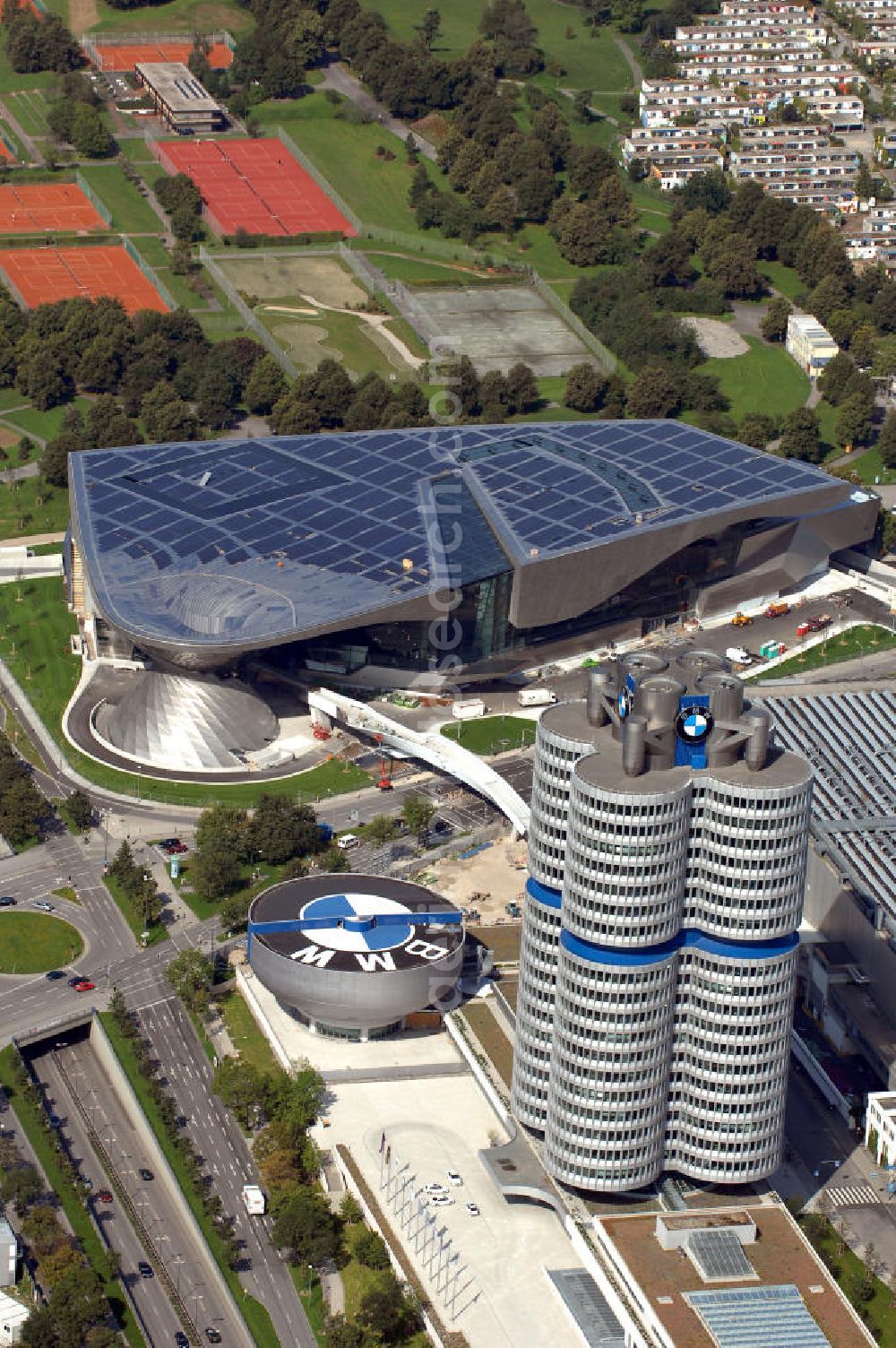 Aerial image München - Der BMW Vierzylinder (auch: BMW-Turm, BMW-Hochhaus) ist das Hauptverwaltungsgebäude und Wahrzeichen des Autoherstellers BMW in München. Die BMW Welt wurde von den Architekten Coop Himmelb(l)au für BMW errichtet. Auf dem Dach ist eine Solaranlage mit 800 KW Leistung installiert. Genutzt wird das Gebäude für Ausstellungen rund um das Thema BMW. Weitere Informationen unter: http://