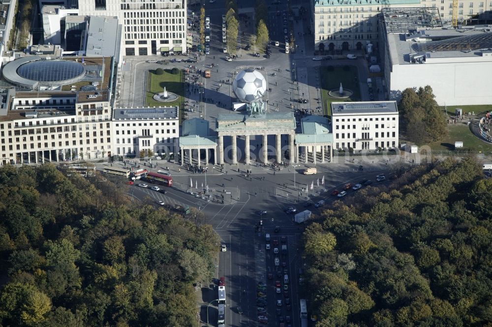 Aerial photograph Berlin - The Brandenburg Gate is on the edge of the Tiergarten at Pariser Platz in the Mitte district of Berlin in the state of Berlin. The Brandenburg Gate is the internationally known landmark of the city and is now the symbol of reunification. The important architectural monument was built by the architect Carl Gotthard Langhans. The sculpture of the Quadriga created by the sculptor Johann Gottfried Schadow. The Brandenburg Gate is an outstanding example of the architectural style of classicism. At the time this photo was a football globe on the Pariser Platz. The design agency 3deluxe had created the art installation as an advertisement for the Soccer World Cup in Germany