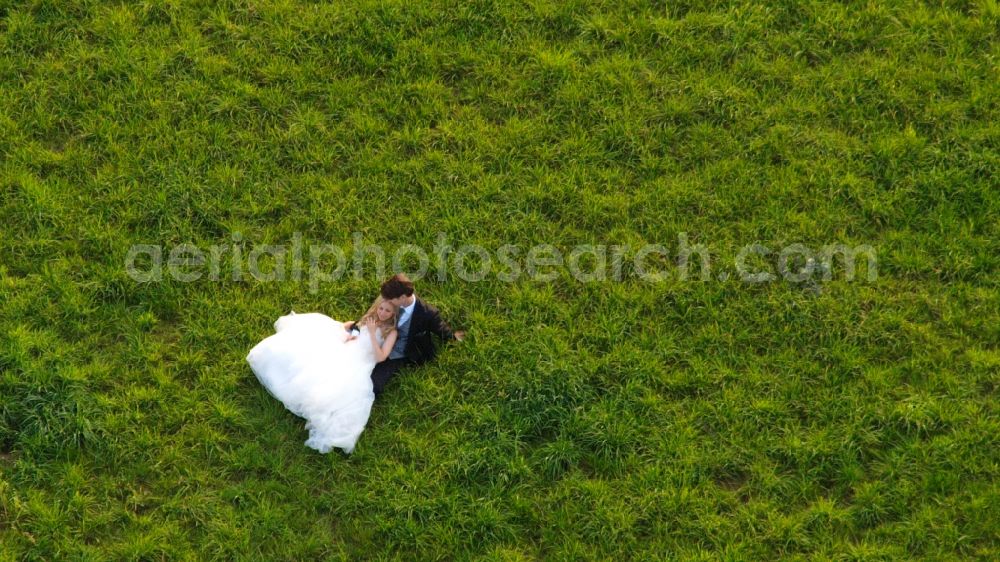 Hennef (Sieg) from above - Bride and groom in wedding dress and suit on a meadow in the state of North Rhine-Westphalia, Germany