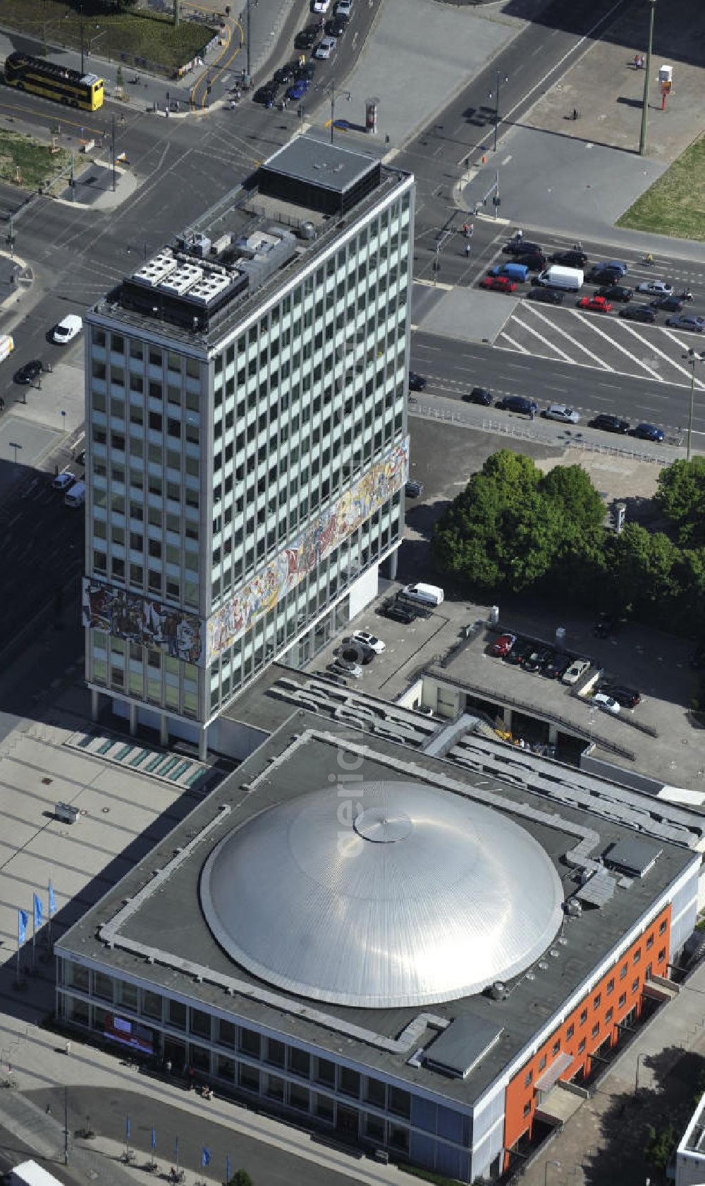 Berlin from the bird's eye view: Blick auf das Bürogebäude - Hochhaus Haus des Lehrers mit der Kongresshalle des Berliner Congress Center (bcc) am Alexanderplatz in Mitte. Die Besonderheit des Gebäudes ist ein umlaufender Fries zwischen dem zweiten und fünften Obergeschoss, im Volksmund „Bauchbinde“ genannt. Dieser von Walter Womacka in Anlehnung an mexikanische Wandbilder entworfene Fries mit dem Namen Unser Leben zeigt Darstellungen aus dem gesellschaftlichen Leben in der DDR. Mit sieben Metern Höhe und 125 Metern Länge zählt es zu den größten Kunstwerken Europas. Der gesamte Gebäudekomplex der WBM Wohnungsbaugesellschaft Berlin-Mitte mbH steht unter Denkmalschutz. Office building - building the teacher's house with the Congress Hall of the Berliner Congress Center in Berlin - Mitte.