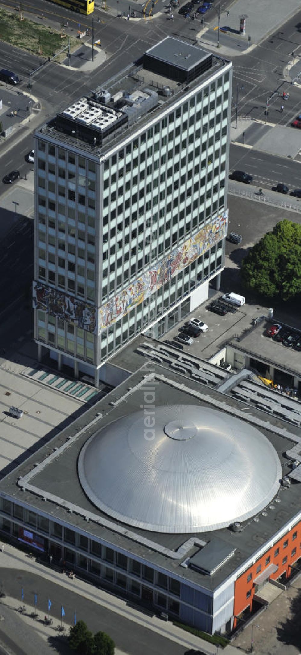 Aerial image Berlin - Blick auf das Bürogebäude - Hochhaus Haus des Lehrers mit der Kongresshalle des Berliner Congress Center (bcc) am Alexanderplatz in Mitte. Die Besonderheit des Gebäudes ist ein umlaufender Fries zwischen dem zweiten und fünften Obergeschoss, im Volksmund „Bauchbinde“ genannt. Dieser von Walter Womacka in Anlehnung an mexikanische Wandbilder entworfene Fries mit dem Namen Unser Leben zeigt Darstellungen aus dem gesellschaftlichen Leben in der DDR. Mit sieben Metern Höhe und 125 Metern Länge zählt es zu den größten Kunstwerken Europas. Der gesamte Gebäudekomplex der WBM Wohnungsbaugesellschaft Berlin-Mitte mbH steht unter Denkmalschutz. Office building - building the teacher's house with the Congress Hall of the Berliner Congress Center in Berlin - Mitte.