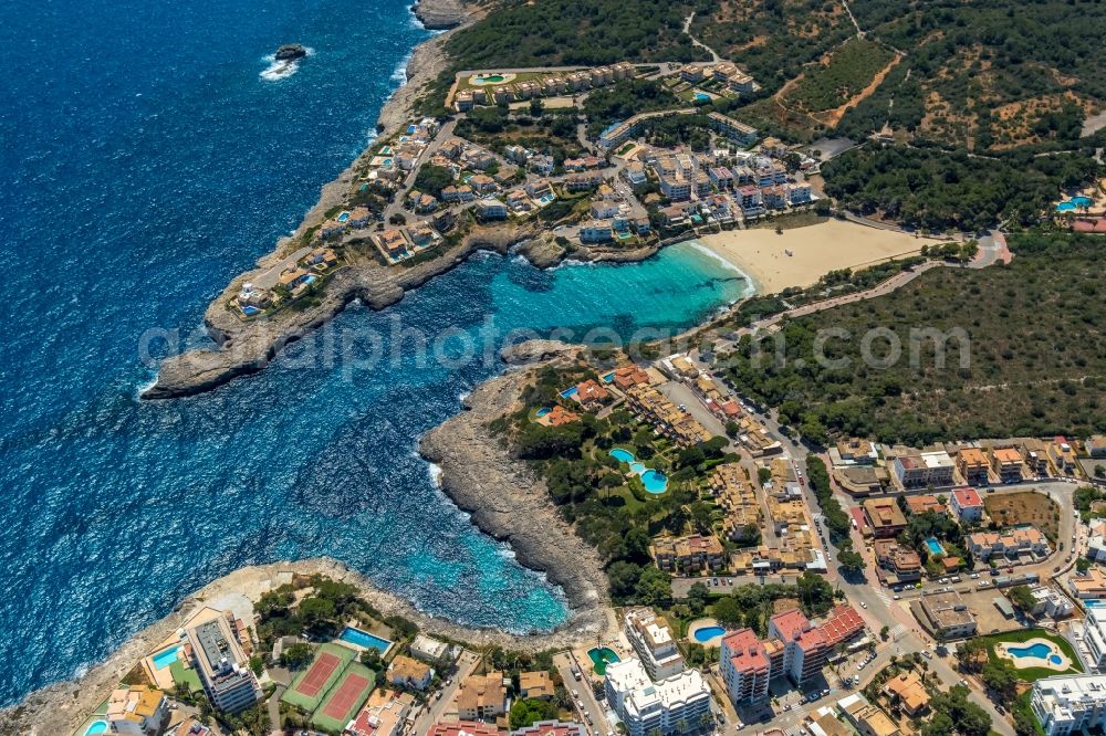 Portocolom from above - Water surface at the bay along the sea coast on the beach Platja de Cala Marcal with hotel complexes and holiday homes in Portocolom in Balearic island of Mallorca, Spain