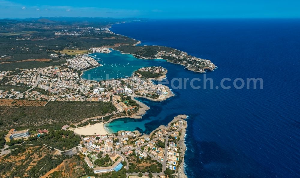 Aerial image Portocolom - Water surface at the bay along the sea coast on the beach Platja de Cala Marcal with hotel complexes and holiday homes in Portocolom in Balearic island of Mallorca, Spain