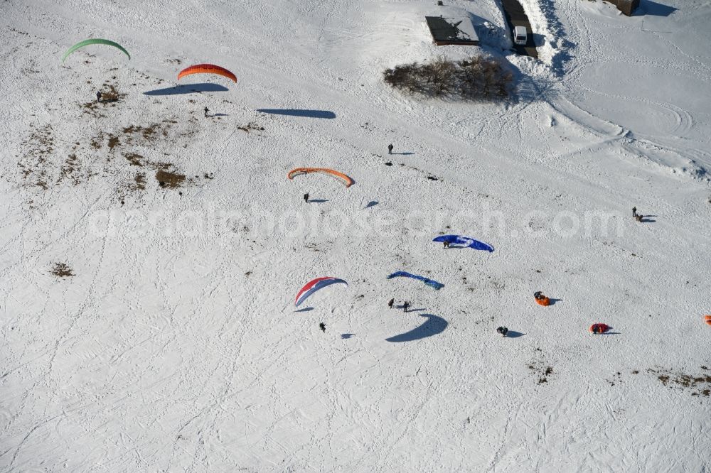 Schmiedefeld am Rennsteig from the bird's eye view: Colorful Paraglider- flyer on a winter with Snowy hillside in Schmiedefeld in Thuringia