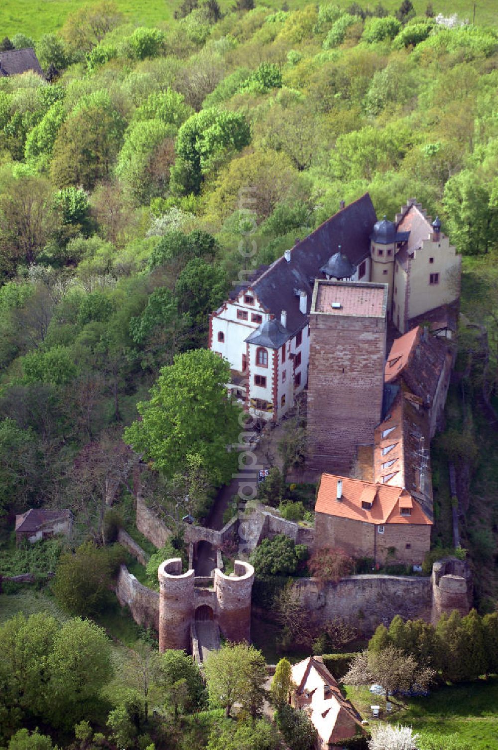 Aerial image GAMBURG - Die Burg Gamburg ist eine Burg bei Gamburg, einem Ortsteil der Gemeinde Werbach, im Main-Tauber-Kreis in Baden-Württemberg. Die Spornburg befindet sich direkt über Gamburg auf einem Bergsporn überhalb der Tauber.Die Burg ist im Privatbesitz und wird bewohnt. Die Burg wurde im 12. Jahrhundert von den Bischöfen von Mainz erbaut, erstmals 1157 als „castrum gamburc“ erwähnt und geht als Mainzer Lehen in den Besitz der Herren von Gamburg. Weitere Besitzer waren Eberhard Rüdt von Collenberg (1546) und Graf von Ingelheim (ab 1701). Seit 1982 ist die Burg im Besitz der Familie Mallinckrodt.Die Burganlage mit ovalem Grundriss besteht aus einem staufischen Bergfried mit einer Grundfläche von 10 x 10 Metern und einer Mauerstärke von 3 Metern, einer romanischen Bausubstanz, Palas mit spätromanischer Ausmalung, Wehrmauern, Tor mit zwei runden Ecktürmen, Halsgraben und einer ovalen Zwingeranlage. Früher befand sich im Palas eine Kapelle.