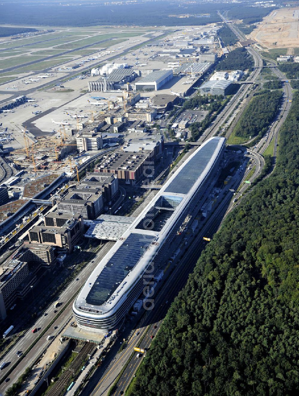 Frankfurt am Main from the bird's eye view: Blick auf das Businesscenter The Squaire, vormals als Airrail Center Frankfurt bekannt. Hauptinvestor für das futuristische Projekt ist die IVG Immobilien AG. Das 660 Meter lange und neun Etagen (45 Meter) hohe Gebäude wurde über dem Fernbahnhof gebaut, um eine zusätzliche Fläche für Büros, Hotels und Einkaufszentren zu bieten. Das u.a. mit der Streif Baulogistik GmbH errichtete Bauwerk ist auf die Decke des Fernbahnhofs gesetzt, die wie die Pfeiler des Grundbauwerks bereits entsprechend ausgelegt wurde. Das Center ist somit direkt mit dem Terminal 1 und dem Fernbahnhof verbunden. View of the Business Center The Squair, formerly known as Airrail Center Frankfurt. The main investor for the futuristic project is the IVG Immobilien AG.