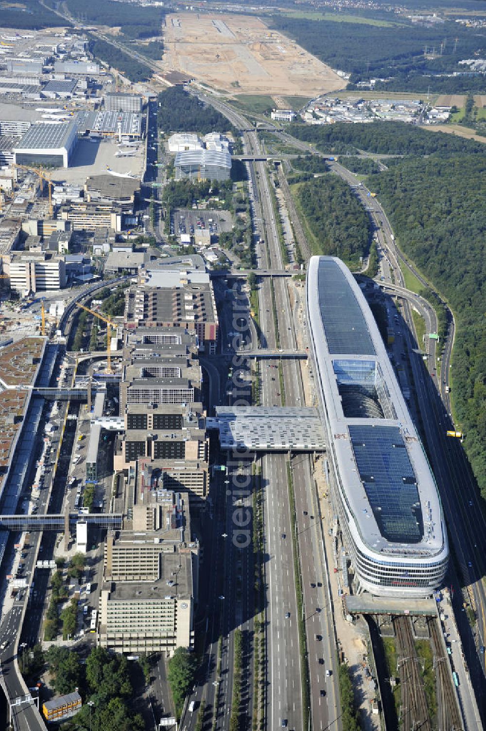 Aerial photograph Frankfurt am Main - Blick auf das Businesscenter The Squaire, vormals als Airrail Center Frankfurt bekannt. Hauptinvestor für das futuristische Projekt ist die IVG Immobilien AG. Das 660 Meter lange und neun Etagen (45 Meter) hohe Gebäude wurde über dem Fernbahnhof gebaut, um eine zusätzliche Fläche für Büros, Hotels und Einkaufszentren zu bieten. Das u.a. mit der Streif Baulogistik GmbH errichtete Bauwerk ist auf die Decke des Fernbahnhofs gesetzt, die wie die Pfeiler des Grundbauwerks bereits entsprechend ausgelegt wurde. Das Center ist somit direkt mit dem Terminal 1 und dem Fernbahnhof verbunden. View of the Business Center The Squair, formerly known as Airrail Center Frankfurt. The main investor for the futuristic project is the IVG Immobilien AG.