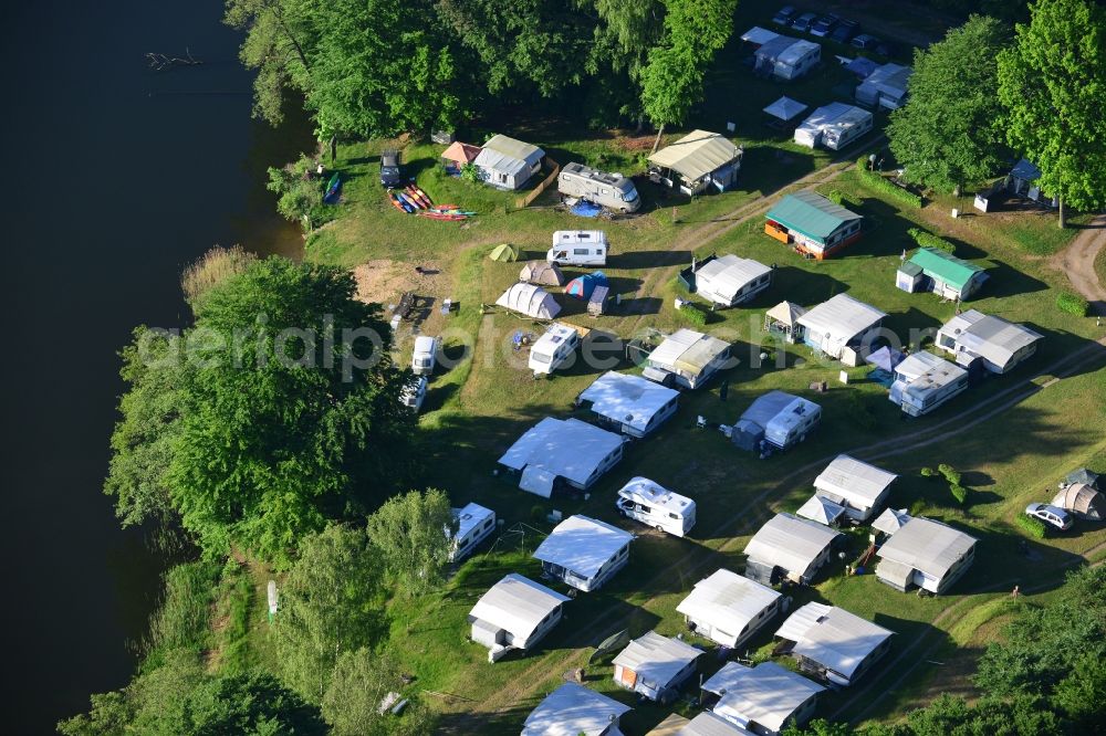 Aerial photograph Neuruppin - Camping with caravans on the lakeside of Zermuetzelsee in Neuruppin in the state of Brandenburg. Neuruppin is the main town of the Ruppiner Land region and capital of the county district of Ostprignitz-Ruppin in the North of the state. The lake is located in the North of the town in the Ruppiner Switzerland region and is surrounded by forest. The white caravans are standing on the lakeside