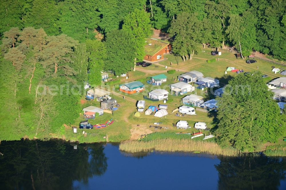 Neuruppin from above - Camping with caravans on the lakeside of Zermuetzelsee in Neuruppin in the state of Brandenburg. Neuruppin is the main town of the Ruppiner Land region and capital of the county district of Ostprignitz-Ruppin in the North of the state. The lake is located in the North of the town in the Ruppiner Switzerland region and is surrounded by forest. The white caravans are standing on the lakeside