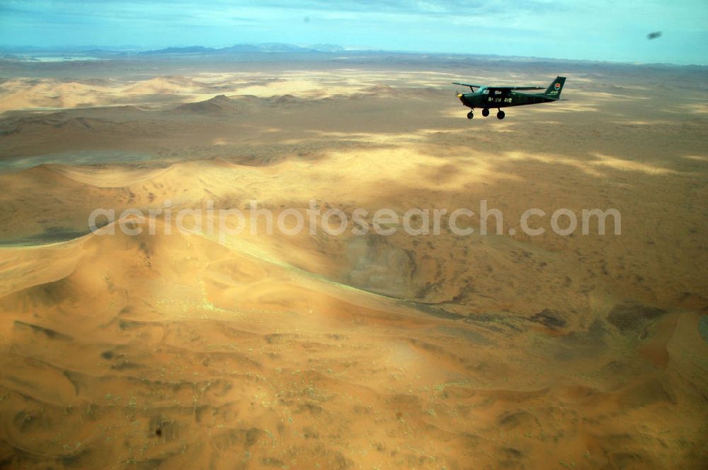 Windhoeck from the bird's eye view: Eine als Buschflieger genutzte Cessna 182 im Formationsflug über der Wüste in Namibia. A Cessna 182 flying low in the surrounding areas of Sandfontein.