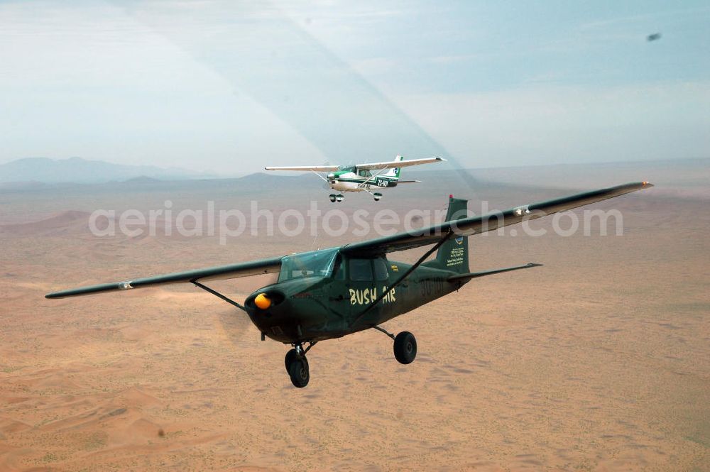 Windhoeck from the bird's eye view: Eine als Buschflieger genutzte Cessna 182 im Formationsflug über der Wüste in Namibia. A Cessna 182 flying low in the surrounding areas of Sandfontein.