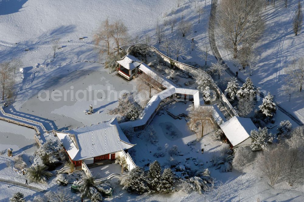 Berlin from the bird's eye view: Blick auf den mit Schnee bedecktem nördlichen Teil des Chinesischen Garten in den Gärten der Welt im Erholungspark Marzahn. Dieser Teil beinhaltet die Eingangshalle „Stube des heiteren Wetters“, die Kleine Halle „Pavillon des ruhigen Mondscheins“ und das Teehaus „Berghaus zum Osmanthussaft“, mit Zick-Zack Brücke. Der kleine See ist zugefroren / mit Eis bedeckt. Kontakt: Grün Berlin Park und Garten GmbH, Sangerhauser Weg 1, 12349 Berlin, Tel. +49(0)30 700906 0, Fax +49(0)30 700906 70, E-Mail: info@gruen-berlin.de