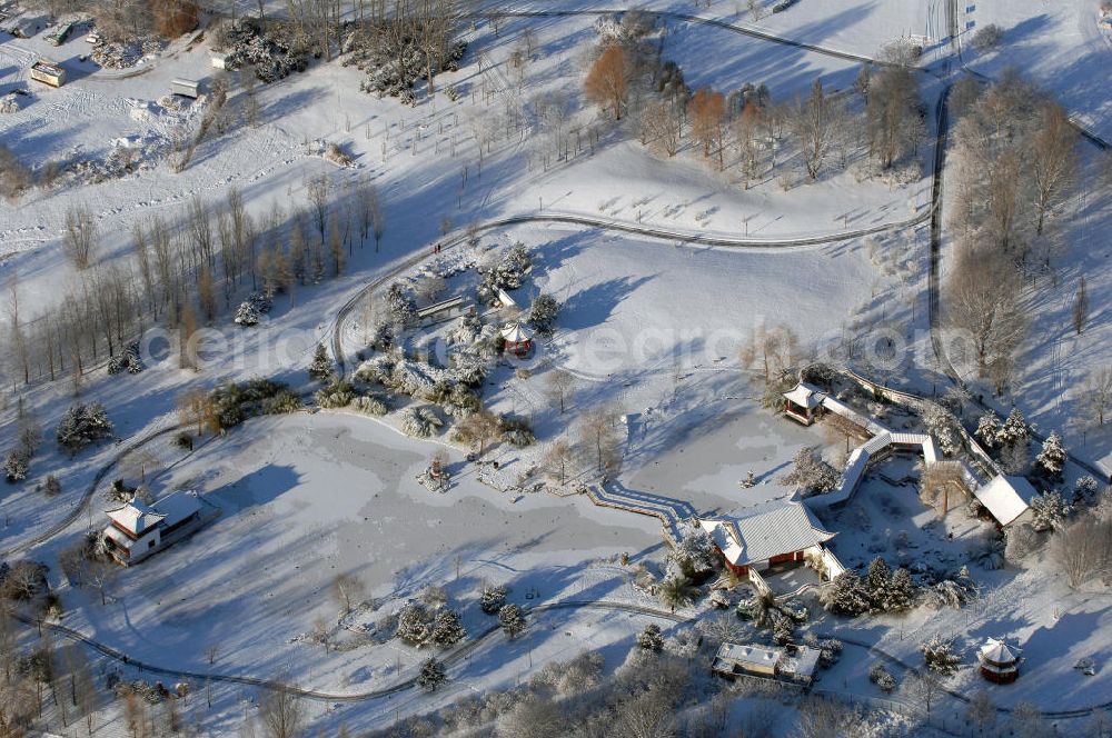 Aerial photograph Berlin - Blick auf den mit Schnee bedecktem Chinesischen Garten in den Gärten der Welt im Erholungspark Marzahn. Dieser Teil beinhaltet die Eingangshalle „Stube des heiteren Wetters“, die Kleine Halle „Pavillon des ruhigen Mondscheins“, das Teehaus „Berghaus zum Osmanthussaft“, mit Zick-Zack Brücke, den Tsingtao-Pavillon, den Oktagonal-Pavillion und dem Steinboot „Blick auf den Mond“. Der kleine See ist zugefroren / mit Eis bedeckt. Kontakt: Grün Berlin Park und Garten GmbH, Sangerhauser Weg 1, 12349 Berlin, Tel. +49(0)30 700906 0, Fax +49(0)30 700906 70, E-Mail: info@gruen-berlin.de