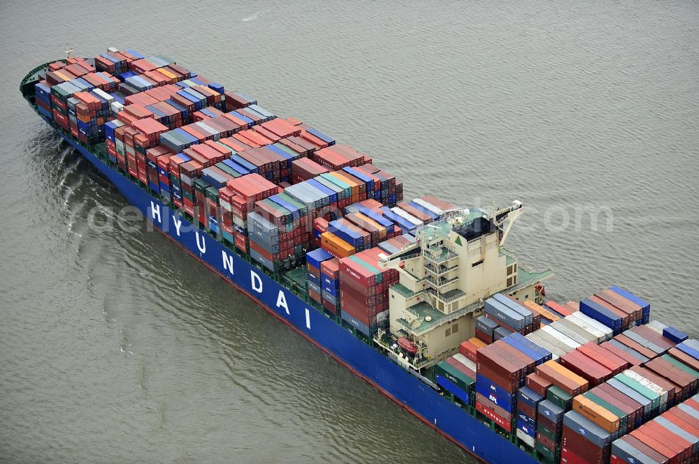 Aerial photograph BRUNSBÜTTEL - Blick auf den von der koreanischen Reederei Hyundai Merchant Marine (HMM) gebauten Containerriese „ HYUNDAI Courage auf der Elbe. Der auf der koreanischen Werft Hyundai Heavy Industries gebaute Containerriese ist 339 m lang, 45,60 m breit und verfügt über eine Stellplatzkapazität von knapp 8566 TEU (20-Fuß-Standardcontainer). Der maximale Tiefgang der „Hyundai Courage beträgt 14,50 m. View of the Korean from the shipping company Hyundai Merchant Marine (HMM) built container giant HYUNDAI Courage on the Elbe.