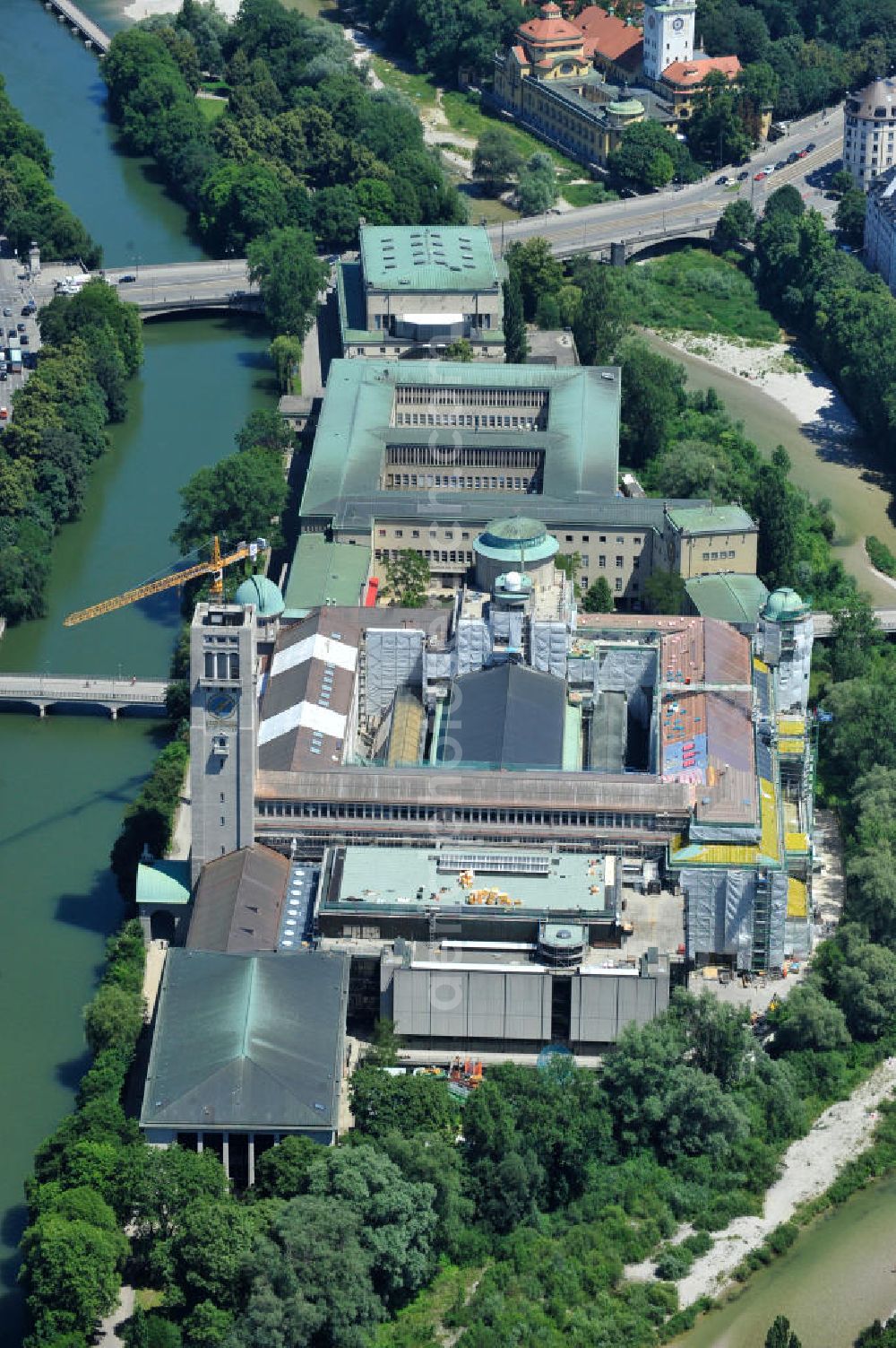 München from above - Blick auf das Deutsche Museum auf der Museumsinsel an der Isar an der Ludwigsbrücke. Derzeit laufen umfangreiche Fassadensanierungsarbeiten und die Neueindeckung des kompletten Dachaufbaus mit einem Kupferdach. Das Deutsche Museum (offizieller Name: Deutsches Museum von Meisterwerken der Naturwissenschaft und Technik) in München ist das größte naturwissenschaftlich-technische Museum der Welt. Es werden rund 28.000 Objekte aus etwa 50 Bereichen der Naturwissenschaften und der Technik ausgestellt, die jährlich von etwa 1,5 Millionen Menschen besucht werden. Die Forschungseinrichtung ist Mitglied der Leibniz-Gemeinschaft. View the German Museum on Museum Island in the Isar River in Munich.