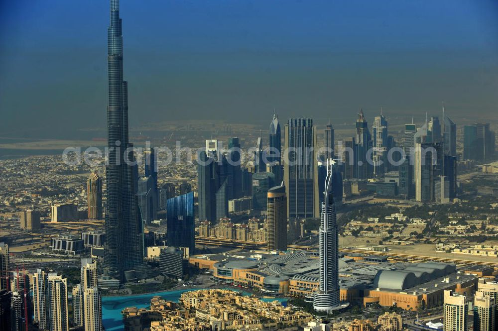 DUBAI / DUBAYY from above - Blick auf das Burj Khalifa in der Skyline von Dubai, dem derzeit höchsten Gebäude der Welt. Das Hochhaus wurde von der Projektgesellschaft Emaar Properties nach Plänen des Architekten Adrian Smith vom amerikanischen Architekturbüro Skidmore, Owings and Merrill gebaut. Das Hochhaus ist Mittelpunkt von Downtown Dubai, eines neuen Stadtentwicklungsgebietes.Rechts die Dubai Mall, das derzeit zweitgrößtem Einkaufszentrum der Welt. Die Dubai Mall wurde konzipiert von Emaar Properties in einem Areal von Apartment- und Bürogebäuden, zahlreiche Hotels und eine neu gebaute, arabisch wirkende Altstadt mit Wasserbeckenlandschaft und der weltgrößten Springbrunnenanlage. Aerial view of the Burj Khalifa and the shopping mall Dubai Mall, currently the second largest shopping center in the world in the new Downtown Dubai district.