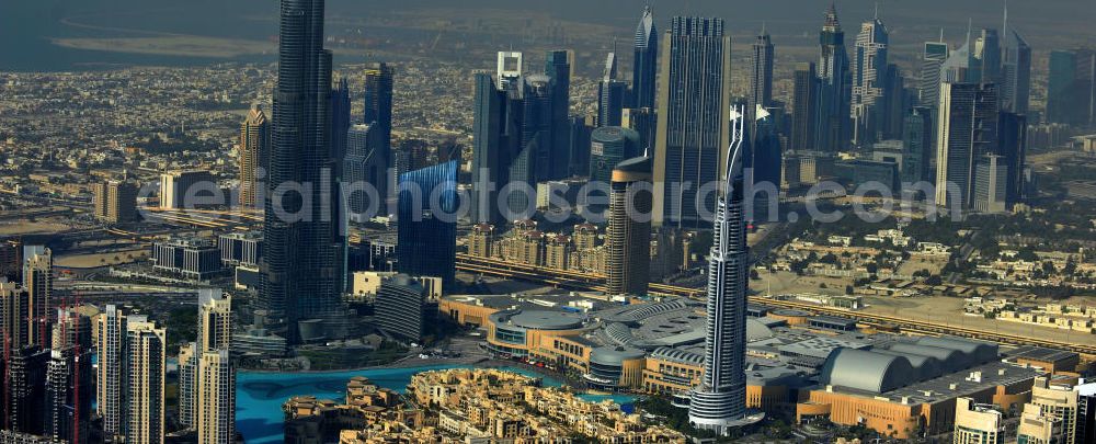 DUBAI / DUBAYY from the bird's eye view: Blick auf das Burj Khalifa in der Skyline von Dubai, dem derzeit höchsten Gebäude der Welt. Das Hochhaus wurde von der Projektgesellschaft Emaar Properties nach Plänen des Architekten Adrian Smith vom amerikanischen Architekturbüro Skidmore, Owings and Merrill gebaut. Das Hochhaus ist Mittelpunkt von Downtown Dubai, eines neuen Stadtentwicklungsgebietes.Rechts die Dubai Mall, das derzeit zweitgrößtem Einkaufszentrum der Welt. Die Dubai Mall wurde konzipiert von Emaar Properties in einem Areal von Apartment- und Bürogebäuden, zahlreiche Hotels und eine neu gebaute, arabisch wirkende Altstadt mit Wasserbeckenlandschaft und der weltgrößten Springbrunnenanlage. Aerial view of the Burj Khalifa and the shopping mall Dubai Mall, currently the second largest shopping center in the world in the new Downtown Dubai district.