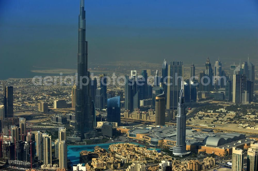 Aerial image DUBAI / DUBAYY - Blick auf das Burj Khalifa in der Skyline von Dubai, dem derzeit höchsten Gebäude der Welt. Das Hochhaus wurde von der Projektgesellschaft Emaar Properties nach Plänen des Architekten Adrian Smith vom amerikanischen Architekturbüro Skidmore, Owings and Merrill gebaut. Das Hochhaus ist Mittelpunkt von Downtown Dubai, eines neuen Stadtentwicklungsgebietes.Rechts die Dubai Mall, das derzeit zweitgrößtem Einkaufszentrum der Welt. Die Dubai Mall wurde konzipiert von Emaar Properties in einem Areal von Apartment- und Bürogebäuden, zahlreiche Hotels und eine neu gebaute, arabisch wirkende Altstadt mit Wasserbeckenlandschaft und der weltgrößten Springbrunnenanlage. Aerial view of the Burj Khalifa and the shopping mall Dubai Mall, currently the second largest shopping center in the world in the new Downtown Dubai district.