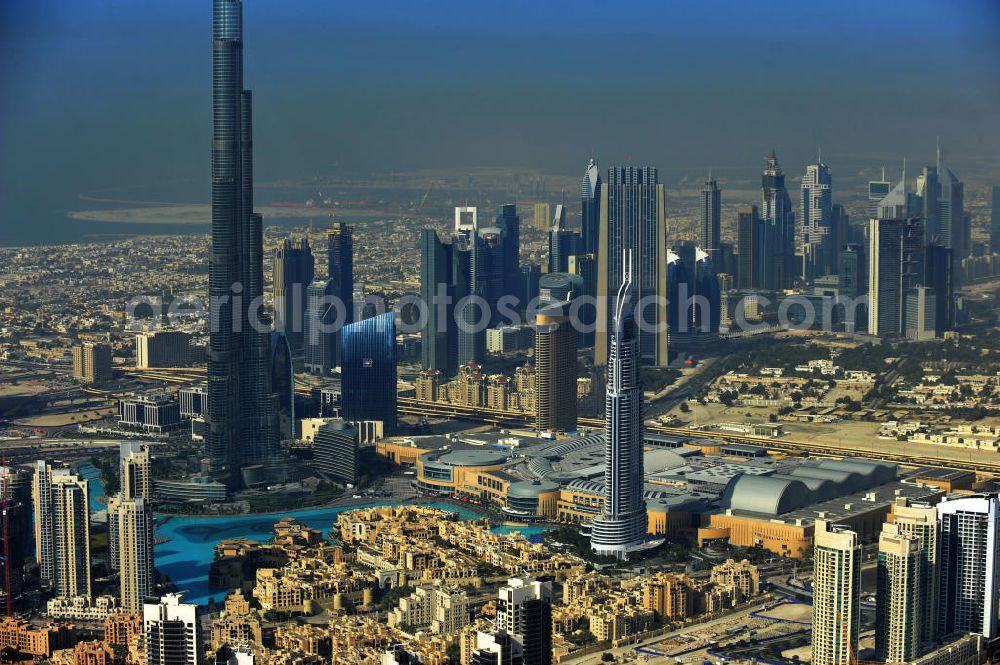 Aerial photograph DUBAI / DUBAYY - Blick auf das Burj Khalifa in der Skyline von Dubai, dem derzeit höchsten Gebäude der Welt. Das Hochhaus wurde von der Projektgesellschaft Emaar Properties nach Plänen des Architekten Adrian Smith vom amerikanischen Architekturbüro Skidmore, Owings and Merrill gebaut. Das Hochhaus ist Mittelpunkt von Downtown Dubai, eines neuen Stadtentwicklungsgebietes.Rechts die Dubai Mall, das derzeit zweitgrößtem Einkaufszentrum der Welt. Die Dubai Mall wurde konzipiert von Emaar Properties in einem Areal von Apartment- und Bürogebäuden, zahlreiche Hotels und eine neu gebaute, arabisch wirkende Altstadt mit Wasserbeckenlandschaft und der weltgrößten Springbrunnenanlage. Aerial view of the Burj Khalifa and the shopping mall Dubai Mall, currently the second largest shopping center in the world in the new Downtown Dubai district.