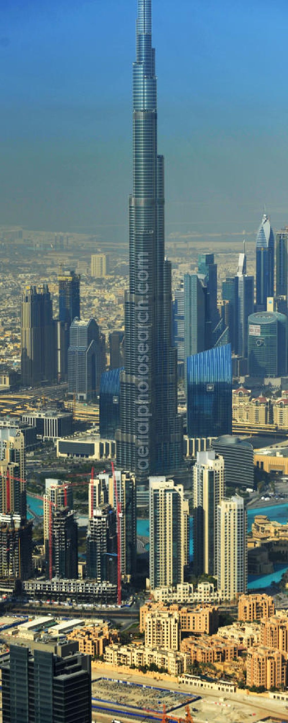 DUBAI / DUBAYY from above - Blick auf das Burj Khalifa in der Skyline von Dubai, dem derzeit höchsten Gebäude der Welt. Das Hochhaus wurde von der Projektgesellschaft Emaar Properties nach Plänen des Architekten Adrian Smith vom amerikanischen Architekturbüro Skidmore, Owings and Merrill gebaut. Das Hochhaus ist Mittelpunkt von Downtown Dubai, eines neuen Stadtentwicklungsgebietes. In den unteren 37 der allgemein nutzbaren 163 Etagen ist das weltweit erste Armani-Hotel eingezogen. Einige tausend Tonnen Stahl in den oberen Geschossen sind Recycling-Stahl aus dem abgerissenen Palast der Republik in Berlin. Die Firma Bauer Spezialtiefbau als Subunternehmer bei der Fundamentlegung. Der verarbeitungsfertige flüssige Beton wurde mit Hochleistungsbetonpumpen der Firma Putzmeister auf die jeweilige Arbeitshöhe transportiert. Skyscraper Burj Khalifa, currently the tallest building in the world.