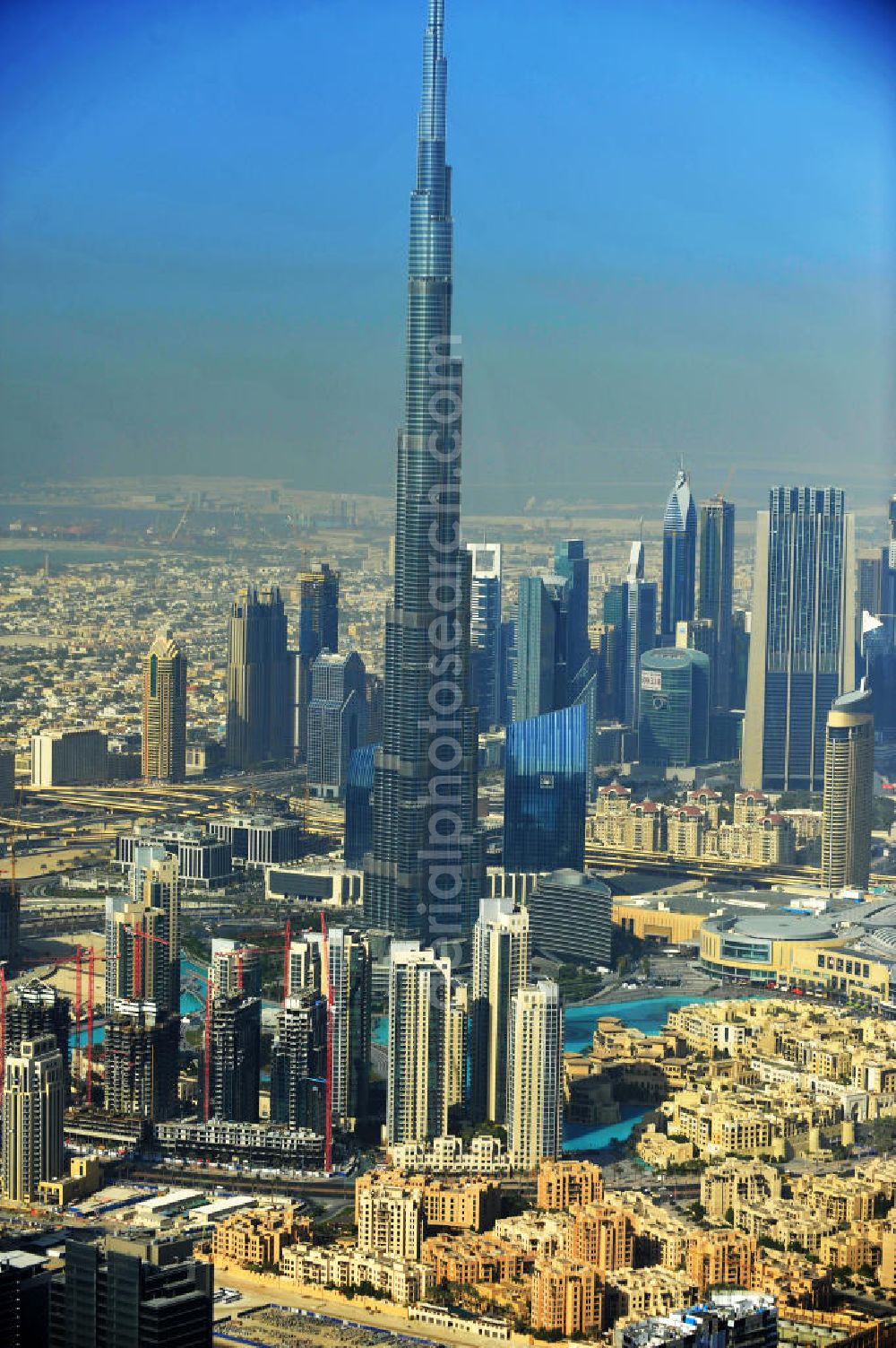 DUBAI / DUBAYY from the bird's eye view: Blick auf das Burj Khalifa in der Skyline von Dubai, dem derzeit höchsten Gebäude der Welt. Das Hochhaus wurde von der Projektgesellschaft Emaar Properties nach Plänen des Architekten Adrian Smith vom amerikanischen Architekturbüro Skidmore, Owings and Merrill gebaut. Das Hochhaus ist Mittelpunkt von Downtown Dubai, eines neuen Stadtentwicklungsgebietes. In den unteren 37 der allgemein nutzbaren 163 Etagen ist das weltweit erste Armani-Hotel eingezogen. Einige tausend Tonnen Stahl in den oberen Geschossen sind Recycling-Stahl aus dem abgerissenen Palast der Republik in Berlin. Die Firma Bauer Spezialtiefbau als Subunternehmer bei der Fundamentlegung. Der verarbeitungsfertige flüssige Beton wurde mit Hochleistungsbetonpumpen der Firma Putzmeister auf die jeweilige Arbeitshöhe transportiert. Skyscraper Burj Khalifa, currently the tallest building in the world.