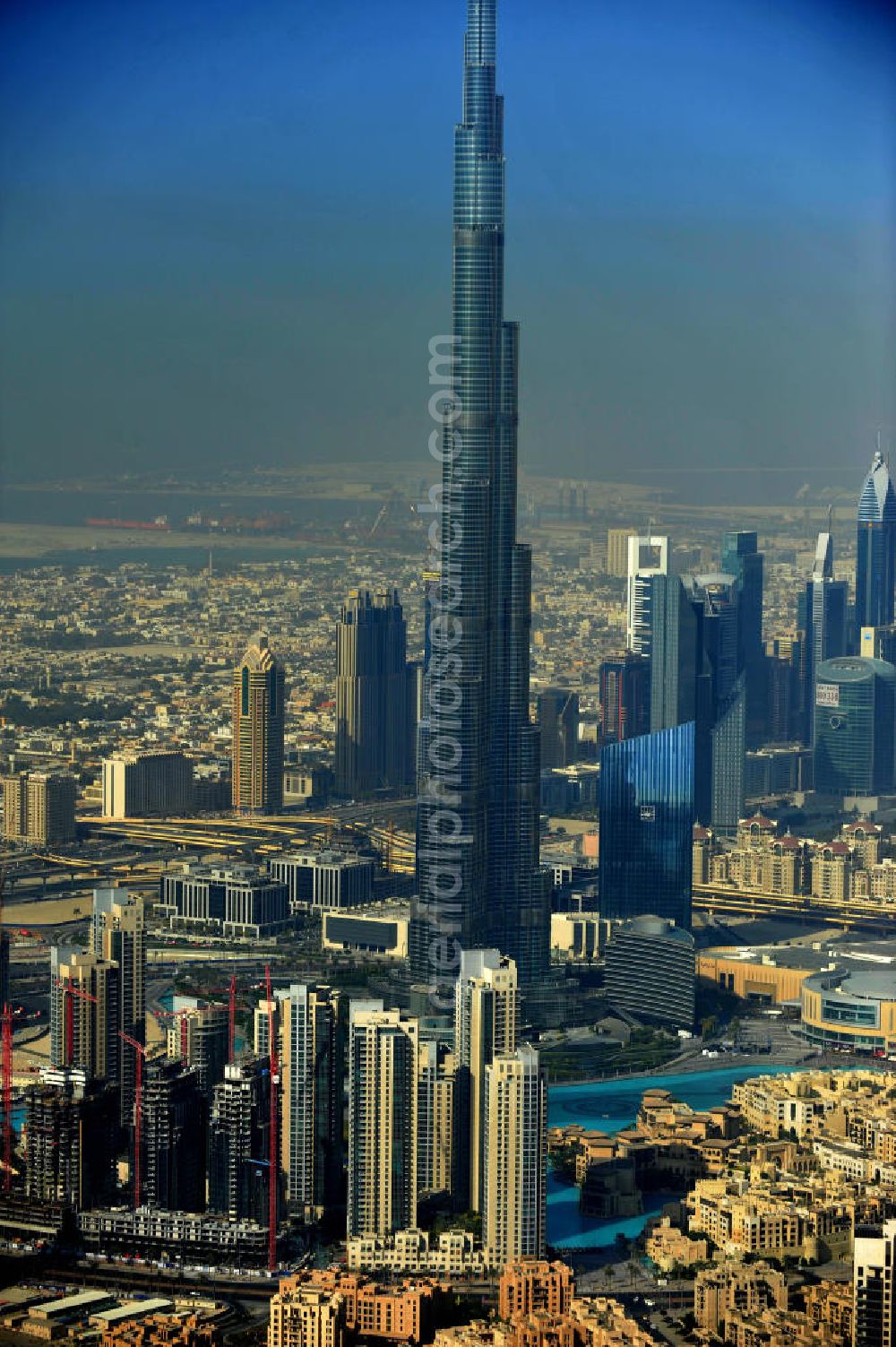 Aerial photograph DUBAI / DUBAYY - Blick auf das Burj Khalifa in der Skyline von Dubai, dem derzeit höchsten Gebäude der Welt. Das Hochhaus wurde von der Projektgesellschaft Emaar Properties nach Plänen des Architekten Adrian Smith vom amerikanischen Architekturbüro Skidmore, Owings and Merrill gebaut. Das Hochhaus ist Mittelpunkt von Downtown Dubai, eines neuen Stadtentwicklungsgebietes. In den unteren 37 der allgemein nutzbaren 163 Etagen ist das weltweit erste Armani-Hotel eingezogen. Einige tausend Tonnen Stahl in den oberen Geschossen sind Recycling-Stahl aus dem abgerissenen Palast der Republik in Berlin. Die Firma Bauer Spezialtiefbau als Subunternehmer bei der Fundamentlegung. Der verarbeitungsfertige flüssige Beton wurde mit Hochleistungsbetonpumpen der Firma Putzmeister auf die jeweilige Arbeitshöhe transportiert. Skyscraper Burj Khalifa, currently the tallest building in the world.