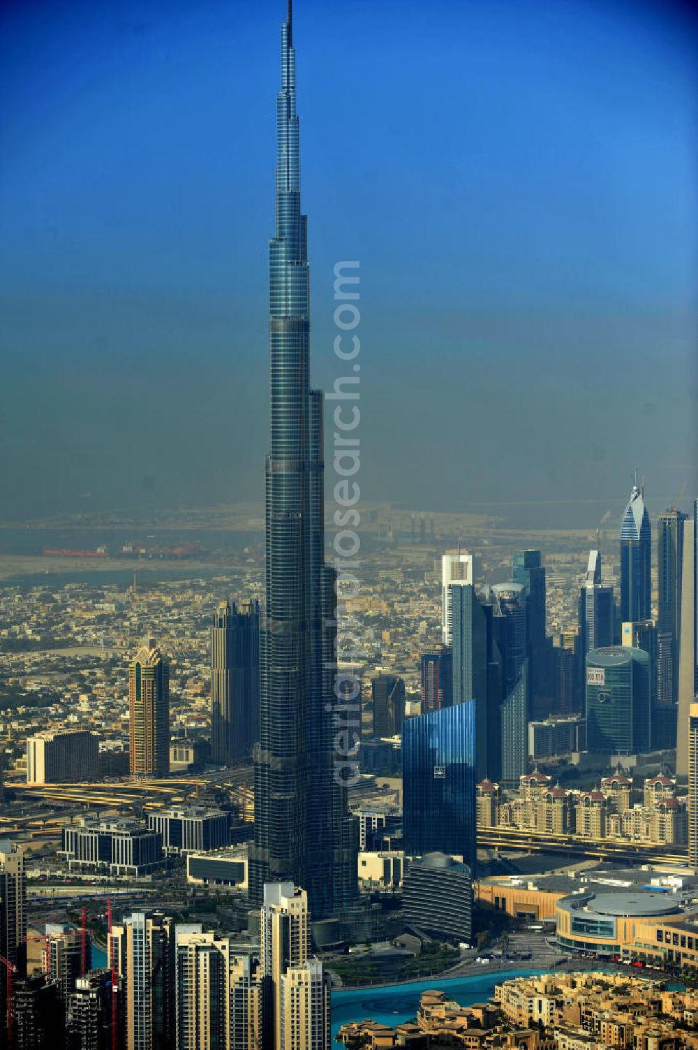 DUBAI / DUBAYY from above - Blick auf das Burj Khalifa in der Skyline von Dubai, dem derzeit höchsten Gebäude der Welt. Das Hochhaus wurde von der Projektgesellschaft Emaar Properties nach Plänen des Architekten Adrian Smith vom amerikanischen Architekturbüro Skidmore, Owings and Merrill gebaut. Das Hochhaus ist Mittelpunkt von Downtown Dubai, eines neuen Stadtentwicklungsgebietes. In den unteren 37 der allgemein nutzbaren 163 Etagen ist das weltweit erste Armani-Hotel eingezogen. Einige tausend Tonnen Stahl in den oberen Geschossen sind Recycling-Stahl aus dem abgerissenen Palast der Republik in Berlin. Die Firma Bauer Spezialtiefbau als Subunternehmer bei der Fundamentlegung. Der verarbeitungsfertige flüssige Beton wurde mit Hochleistungsbetonpumpen der Firma Putzmeister auf die jeweilige Arbeitshöhe transportiert. Skyscraper Burj Khalifa, currently the tallest building in the world.