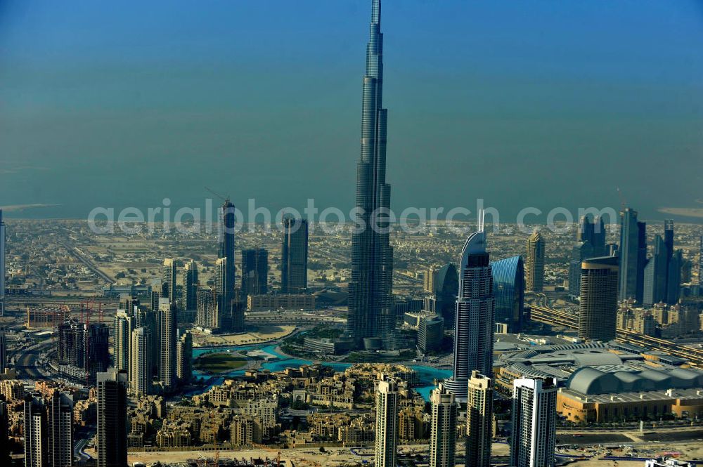 DUBAI / DUBAYY from the bird's eye view: Blick auf das Burj Khalifa in der Skyline von Dubai, dem derzeit höchsten Gebäude der Welt. Das Hochhaus wurde von der Projektgesellschaft Emaar Properties nach Plänen des Architekten Adrian Smith vom amerikanischen Architekturbüro Skidmore, Owings and Merrill gebaut. Das Hochhaus ist Mittelpunkt von Downtown Dubai, eines neuen Stadtentwicklungsgebietes. In den unteren 37 der allgemein nutzbaren 163 Etagen ist das weltweit erste Armani-Hotel eingezogen. Einige tausend Tonnen Stahl in den oberen Geschossen sind Recycling-Stahl aus dem abgerissenen Palast der Republik in Berlin. Die Firma Bauer Spezialtiefbau als Subunternehmer bei der Fundamentlegung. Der verarbeitungsfertige flüssige Beton wurde mit Hochleistungsbetonpumpen der Firma Putzmeister auf die jeweilige Arbeitshöhe transportiert. Skyscraper Burj Khalifa, currently the tallest building in the world.