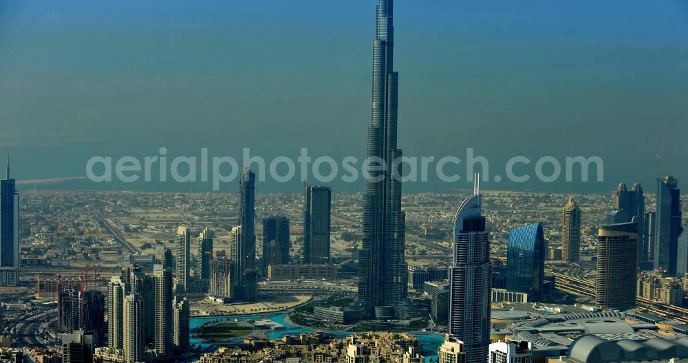 Aerial image DUBAI / DUBAYY - Blick auf das Burj Khalifa in der Skyline von Dubai, dem derzeit höchsten Gebäude der Welt. Das Hochhaus wurde von der Projektgesellschaft Emaar Properties nach Plänen des Architekten Adrian Smith vom amerikanischen Architekturbüro Skidmore, Owings and Merrill gebaut. Das Hochhaus ist Mittelpunkt von Downtown Dubai, eines neuen Stadtentwicklungsgebietes. In den unteren 37 der allgemein nutzbaren 163 Etagen ist das weltweit erste Armani-Hotel eingezogen. Einige tausend Tonnen Stahl in den oberen Geschossen sind Recycling-Stahl aus dem abgerissenen Palast der Republik in Berlin. Die Firma Bauer Spezialtiefbau als Subunternehmer bei der Fundamentlegung. Der verarbeitungsfertige flüssige Beton wurde mit Hochleistungsbetonpumpen der Firma Putzmeister auf die jeweilige Arbeitshöhe transportiert. Skyscraper Burj Khalifa, currently the tallest building in the world.