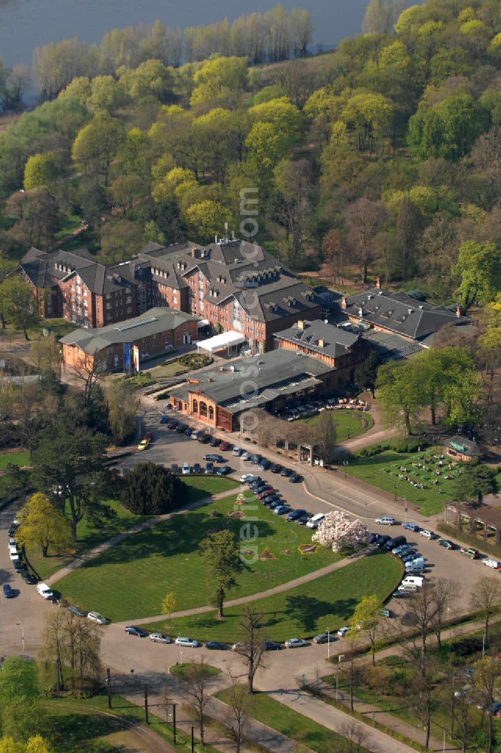 Magdeburg from above - Blick auf das Herrenkrug Parkhotel an der Elbe. Die erstmalige Erwähnung des Herrenkrugs war im 17. Jahrhundert, als Wirtshaus. Die Umliegende Parkanlage entwickelte sich im 19. Jahrhundert zum Ausflugsziel und das Restaurant wurde zu einem der größten in Deutschland. Der Park wird 1995 unter Denkmalschutz gestellt. Das heutige Hotel entstand in den 1990er Jahren und wurde mit dem Architekturpreis ausgezeichnet. Das 4 Sterne Hotel liegt direkt am Ufer der Elbe. Es bietet einen Wellness- und Spa Bereich, sowie Seminar- und Konferenzräume. Kontakt: Herrenkrug GmbH, Herrenkrug Parkhotel an der Elbe, Herrenkrug 3, 39114 Magdeburg, Tel. 0391 / 85 08 0, info@herrenkrug.de