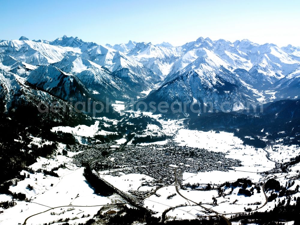 Aerial image Oberstdorf - The winterly and snow covered Oberstdorf in the county district of Oberallgäu in the state of Bavaria. Oberstdorf is the southern most county of Germany and is located in the Allgäu Alps, visible in the background. Oberstdorf is surrounded by ski resorts and areas and owns a famous ski jumping arena