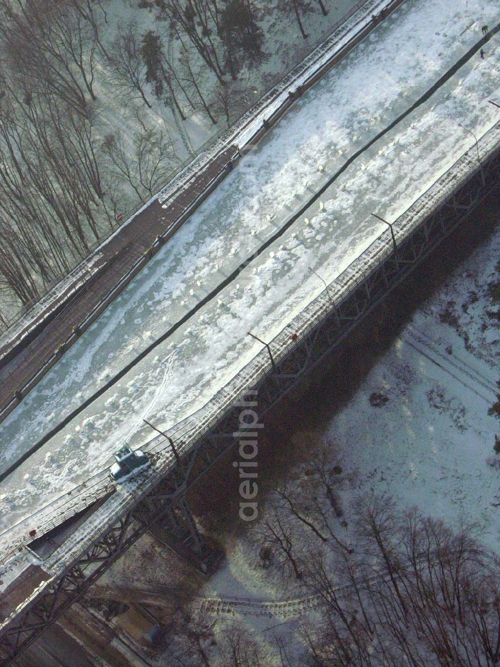 Aerial photograph Niederfinow / BRB - Der anhaltende Dauerfrost macht vor allem dem Personal des Schiffshebewerkes Niederfinow ordentlich zu schaffen. Im Bereich der Trogbrücke muß eine stündlich von Hand erneuerte Wasserrinne freigehalten werden, um mechanische Beschädigungen bei vollständiger Eisbildung auszuschließen. Das Schiffshebewerk ist bis heute ein wichtiger Teil der Wasserstrasse von der Havel bis zur Oder und seine Kapazität stößt an Grenzen. Natürlich wird bei hoher Beanstpruchung auch das Material müde, und somit kam es zuerst in den 80er Jahren zu einer Generalüberhohlung der Zugseile, Seilscheiben, Dichtungen und Antriebsmotoren. Allerdings ist es erstaunlich, daß keine nennenswerten Defekte von der Errichtung bis heute aufgetreten sind. Es ist eben ein Qualitätszeugnis der damaligen Industrie und des Handwerks. Das Schiffshebewerk Niederfinow stößt natürlich bereits seit langer Zeit an seine Kapazität. Aus diesem Grund steht bereits seit einigen Jahren ein neues Schiffshebewerk in Planung. In den nächsten 2Jahren soll voraussichtlich der Baubeginn sein. Es entsteht zwischen dem alten Schiffshebewerk und der alten Schleusentreppe.