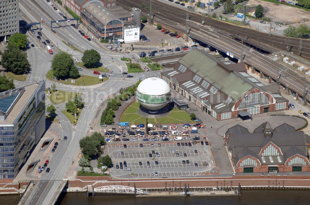 Aerial photograph Hamburg - Blick auf die Deichtorhallen und den Highflyer Fesselballon. Davor ist ein Flohmarkt aufgebaut. Die Deichtorhallen sind Europas größte Kunstausstellungshallen und gliedern sich in das Haus der Photographie und eine zweite Ausstellungshalle für aktuelle Kunst. Hier finden nicht nur Ausstellungen schon großer und namhafter Künstler statt, auch junge noch unbekannte Künstler bekommen immer wieder die Möglichkeit ihre Werke in einem recht großen Rahmen auszustellen. Neben den Ausstellungsräumen gibt es auch einen Design- und Buchshop der Photographie, sowie ein Restaurant. Zwischen den beiden Gebäuden der Deichtorhallen befindet sich eine weitere Touristenattraktion, der Highflyer Fesselballon. Er ist fest installiert und an einem 180 Meter langen Drahtseil befestigt um immer wieder an der gleichen Stellen landen zu können. Mit ihm können 30 Personen in die Luft steigen und die Aussicht auf und über Hamburg genießen. Kontakt: Deichtorhallen Hamburg GmbH, Deichtorstraße 1-2 20095 Hamburg, Tel. +49(0)40 3210 30,mail@deichtorhallen.de