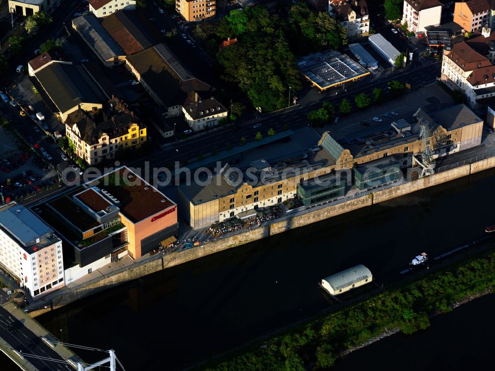 Aerial photograph Würzburg - The old harbour in Würzburg in the Unterfranken region of the state of Bavaria. The compound at the shores of the river Main is in use at least since 1904. The big building on the waterfront is the Kulturspeicher, a former grain silo that is now used as an event location and incorporates a museum. Next to it is a cinema multiplex as well as an IBIS hotel