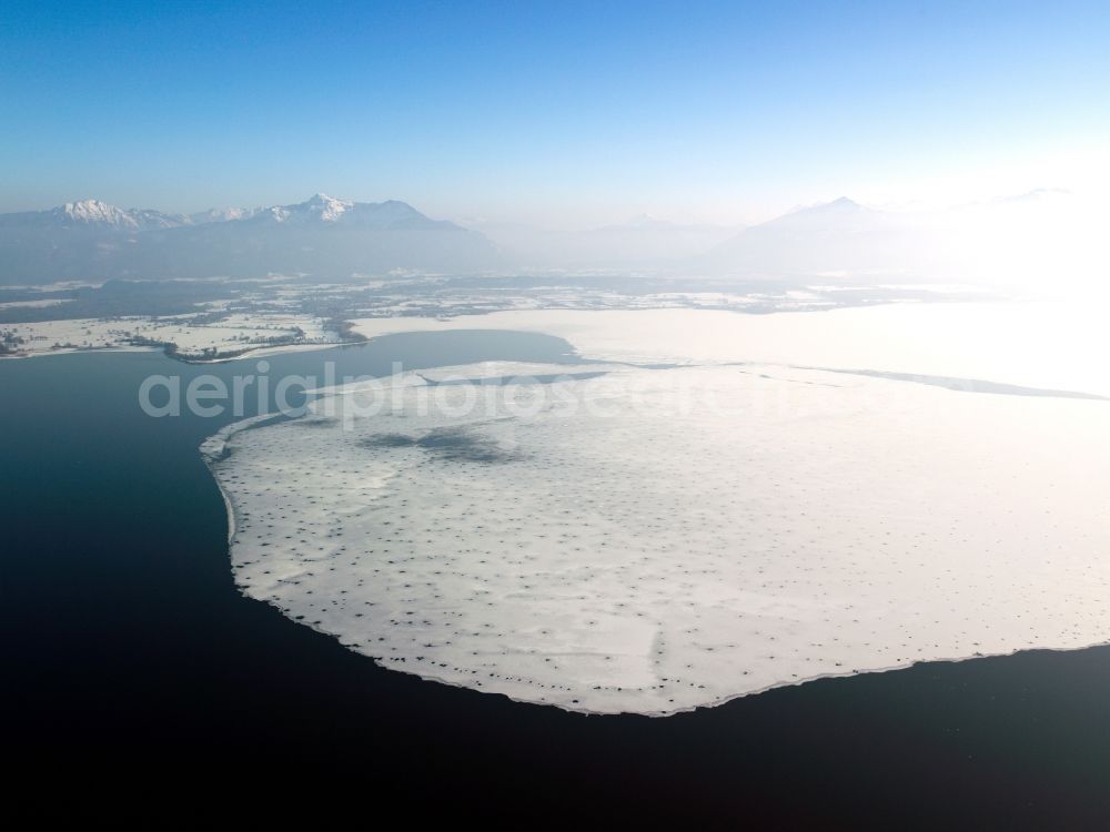 Chiemsee from above - The Chiemsee in the free state of Bavaria. Overview of the winterly, snowed in and frozen lake. The alps are visible in the background. The lake is the largest in Bavaria and the third largest in Germany. It is located in the Chiemgau region, a beloved recreational region and holiday site. The Chiemgauer Mountains are very close by