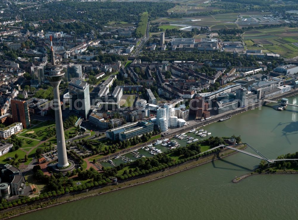 Aerial photograph Düsseldorf - The harbour Medienhafen and the Rhine Tower in Düsseldorf in the state of North Rhine-Westphalia. The actual harbour is an important industrial and inland port. It was partly rebuilt in the 1990s and therefore made the new Medienhafen area. Here are various media and advertising companies, as well as designers and fashion business located. There are also clubs and bars