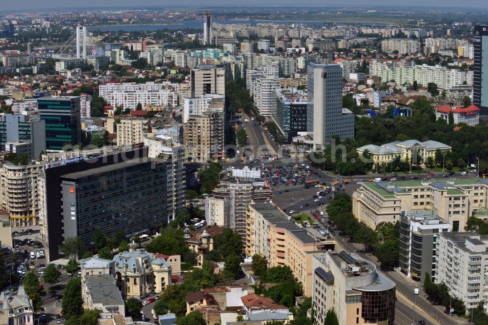 Bukarest from the bird's eye view: The Square Piata Victoriei, the Victory Square, in Sector 1 in Bucharest in Romania. View from the Boulevard Iancu de Hunedoara to the West and the large square and traffic junction, where several large roads of the capital meet and intersect. The square itself consists of several parking lots. An underpass leads the traffic and the street car under the central square. On the Victory square, there are several significant buildings such as the Museum of Natural History Antipa which is surrounded by forest, the Bucharest Tower Center and the BRD Tower, which are the highest buildings of the country. The building with the green roof on the East corner of the square is the Victoria Palace, the government seat of Romania which was built during World War II