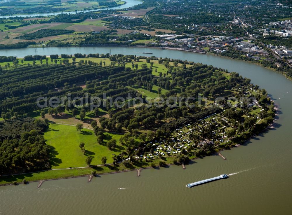 Düsseldorf from the bird's eye view: The Rhine between the city of Düsseldorf on the right, and the town of Dormagen on the left riverbank in the state of North Rhine-Westphalia. The river runs in various bends through the landscape and passes the urban area of Düsseldorf. It circumvents the peninsula which includes the nature preserve area of Zonser Grind, which is located in the Zons part of the town of Dormagen. On the riverbanks, there are various agricultural fields and forests as well as industrial sites and commercial buildings