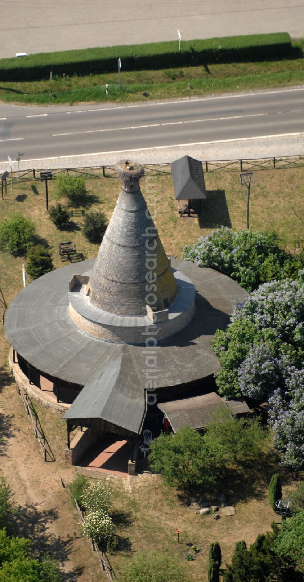 Rathsdorf from the bird's eye view: Blick auf den Storchenturm. Ursprünglich war das Gebäude ein Ziegelbrennofen aus dem 19. Jahrhundert. Nach der Stilllegung vor ca. 100 Jahren bauten Störche ihr Nest auf dem Schornstein. Der Turm ist eines der Wahrzeichen des nördlichen Oderbruchs. Seit 1978 befindet sich im Inneren des Turmes ein Storchenmuseum, das von Kurt Kretschmann begründet wurde. In den 90er Jahren wurde das Gebäude umfassend saniert. Betrieben wird es seit 2003 von der NABU auf ehrenamtlicher Basis. Kontakt: NABU Charitéstraße 3, 10117 Berlin, Tel. 030.284 984 - 0, NABU@NABU.de