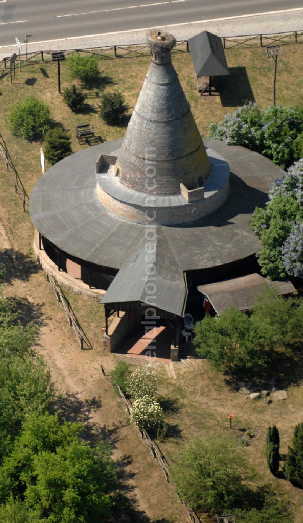 Aerial image Rathsdorf - Blick auf den Storchenturm. Ursprünglich war das Gebäude ein Ziegelbrennofen aus dem 19. Jahrhundert. Nach der Stilllegung vor ca. 100 Jahren bauten Störche ihr Nest auf dem Schornstein. Der Turm ist eines der Wahrzeichen des nördlichen Oderbruchs. Seit 1978 befindet sich im Inneren des Turmes ein Storchenmuseum, das von Kurt Kretschmann begründet wurde. In den 90er Jahren wurde das Gebäude umfassend saniert. Betrieben wird es seit 2003 von der NABU auf ehrenamtlicher Basis. Kontakt: NABU Charitéstraße 3, 10117 Berlin, Tel. 030.284 984 - 0, NABU@NABU.de