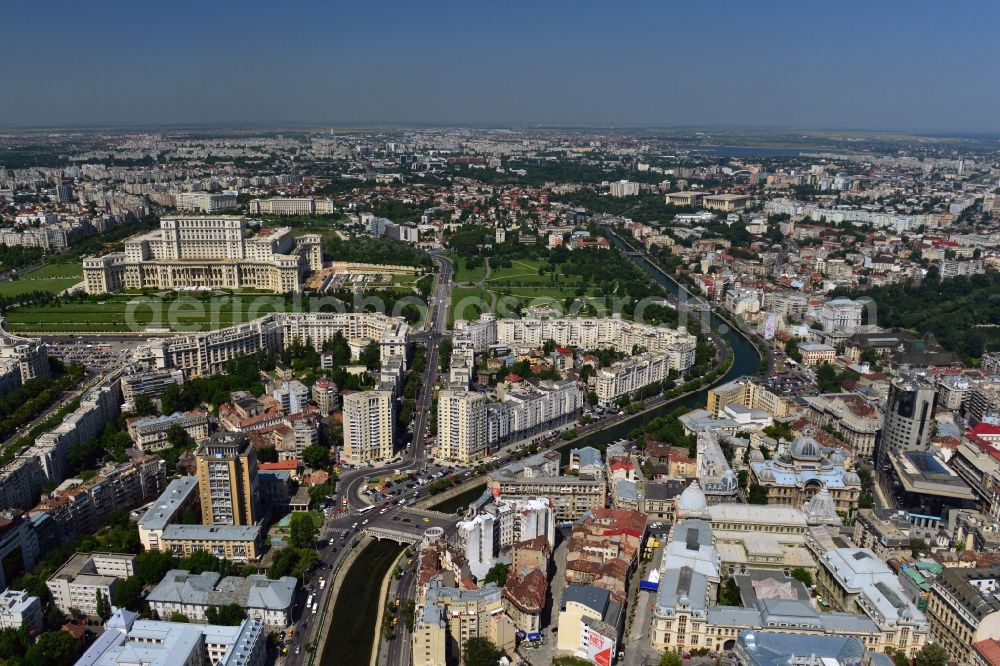 Aerial photograph Bukarest - The run of the river Dambovita in the city center of Bucharest in Romania. The river is regulated in the urban area. On its Southern riverbank there is the Parliament Palace, the largest building in Europe. The National History Museum with its two glas domes and the main building of the national savings bank CEC, the CEC palace, are located on the Northern riverbank