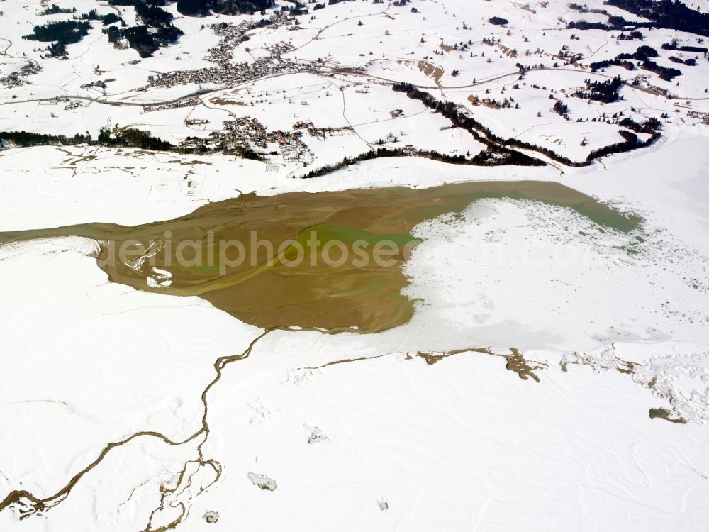 Aerial image Rieden am Forggensee - The snow covered and frozen lake Forggensee at Rieden in the state of Bavaria. The town lies on the shores of the barrier lake of the river Lech in the region of Allgäu. The town has a camping site and boat landing at the West shore of the lake. It is the largest barrier lake of Germany