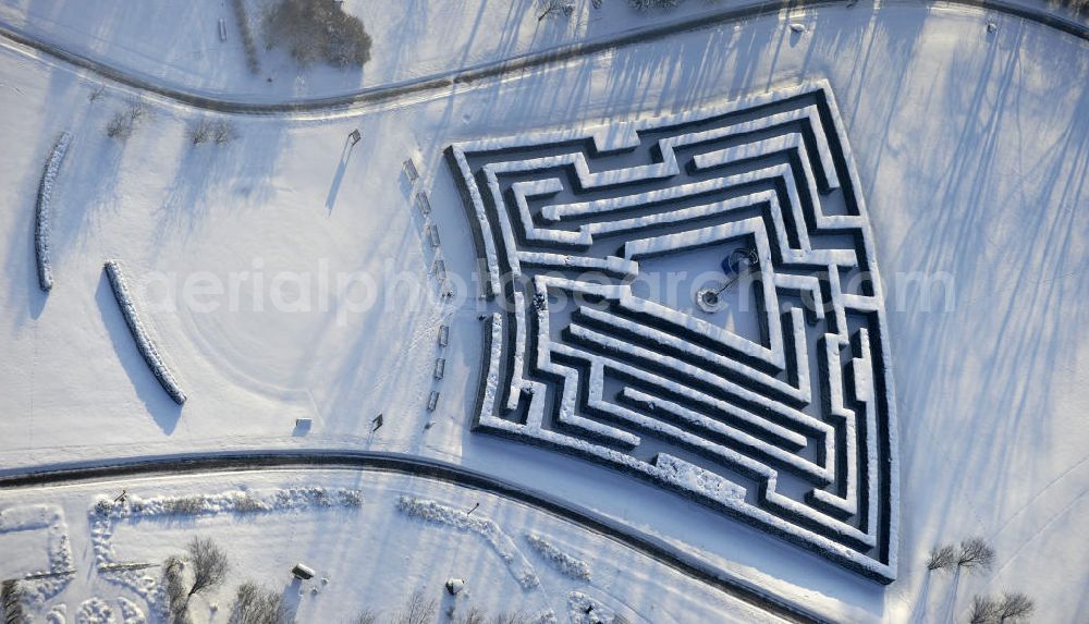 Berlin from above - Blick auf den Irrgarten im Erholungspark Marzahn. Das winterlich verschneite Labyrinth im Erholungspark Marzahn liegt im Berliner Bezirk Marzahn-Hellersdorf am nördlichen Fuß des Kienbergs. 2005 wurde der Chinesische Garten im Erholungspark Marzahn als drittschönste Parkanlage Deutschlands ausgezeichnet. Wintry Labyrinth area of the Marzahn Recreational Park.