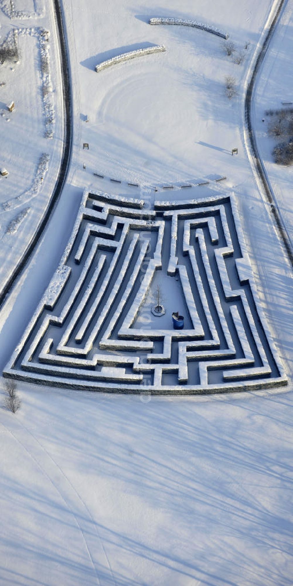 Berlin from above - Blick auf den Irrgarten im Erholungspark Marzahn. Das winterlich verschneite Labyrinth im Erholungspark Marzahn liegt im Berliner Bezirk Marzahn-Hellersdorf am nördlichen Fuß des Kienbergs. 2005 wurde der Chinesische Garten im Erholungspark Marzahn als drittschönste Parkanlage Deutschlands ausgezeichnet. Wintry Labyrinth area of the Marzahn Recreational Park.